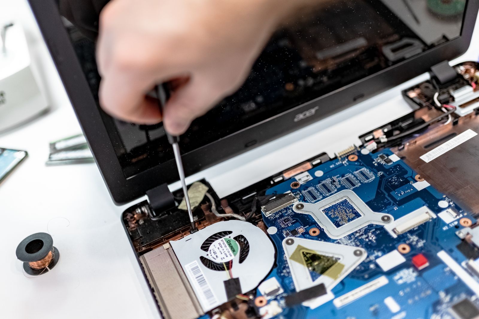 Hands using a screwdriver to repair an open laptop