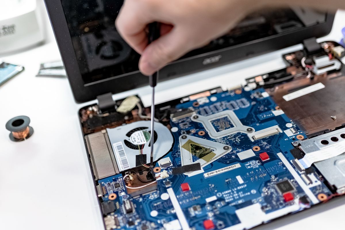 Technician working with a screwdriver inside a laptop